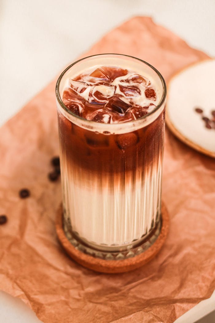 A refreshing iced latte with cream on a brown paper setup, perfect for coffee lovers.